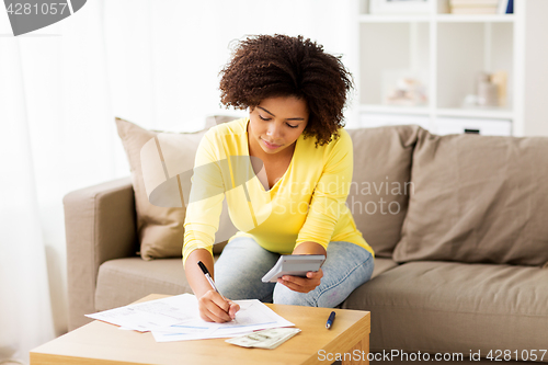 Image of african woman with papers and calculator at home