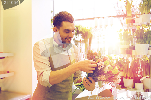 Image of smiling florist man making bunch at flower shop