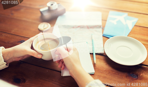 Image of close up of hands with coffee cup and travel stuff