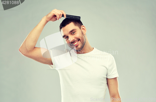 Image of happy man brushing hair with comb over gray