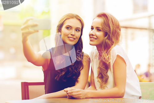 Image of happy women with smartphone taking selfie at cafe