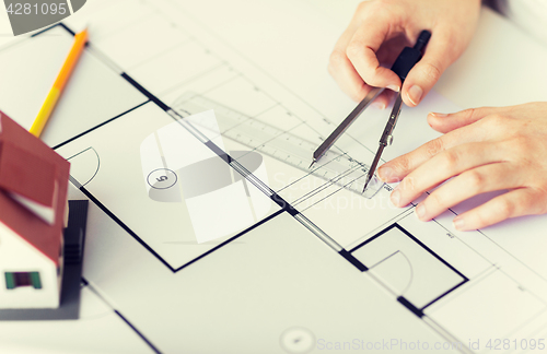 Image of close up of hands with compass measuring blueprint