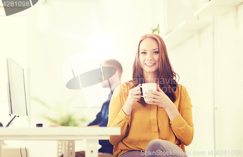 Image of happy woman drinking coffee or tea at office