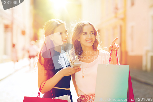 Image of happy women with shopping bags in city