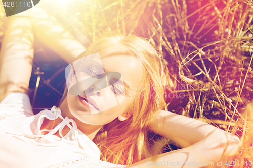 Image of happy young woman lying on cereal field or hay