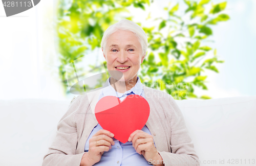 Image of happy smiling senior woman with red heart at home