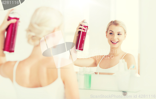 Image of woman with hairspray styling her hair at bathroom