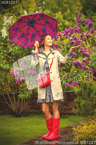 Image of Beautiful woman with an umbrella in red rubber boots
