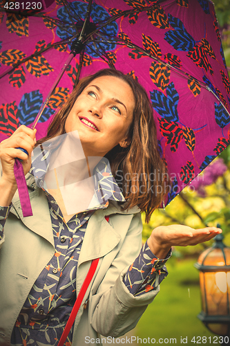 Image of Smiling woman with umbrella in the rain