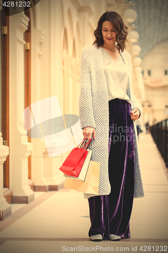 Image of woman in a fashionable knitted coat with shopping bags