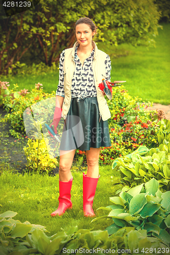 Image of smiling middle-aged woman in red rubber boots planting flowers