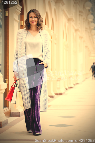 Image of miling beautiful middle aged woman in knitted bright summer coat
