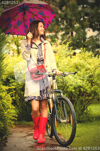 Image of beautiful middle aged woman with umbrella and bicycle