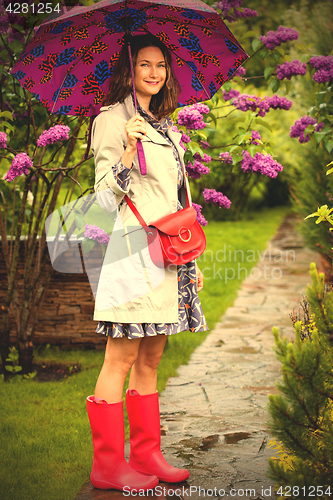 Image of happy middle-aged woman in rubber boots with umbrella