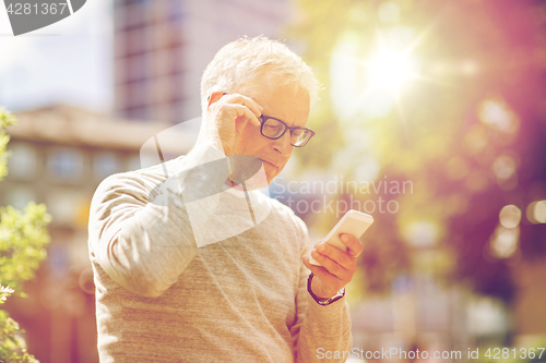 Image of senior man texting message on smartphone in city