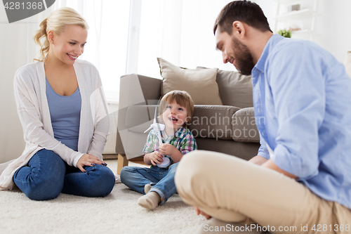 Image of happy family playing with toy wind turbine