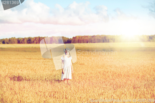 Image of happy young woman in flower wreath on cereal field