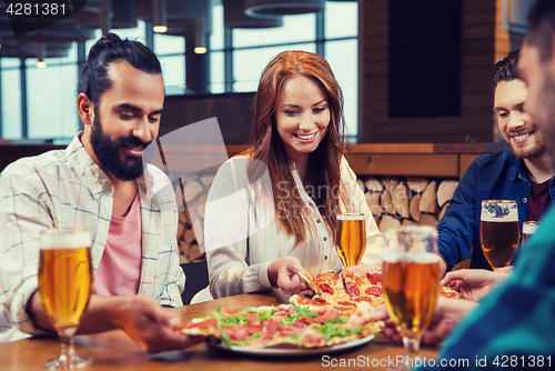 Image of friends eating pizza with beer at restaurant