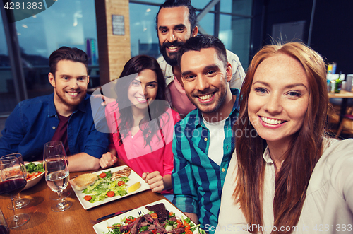 Image of friends taking selfie by smartphone at restaurant