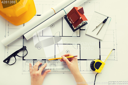 Image of close up of hands with ruler measuring blueprint