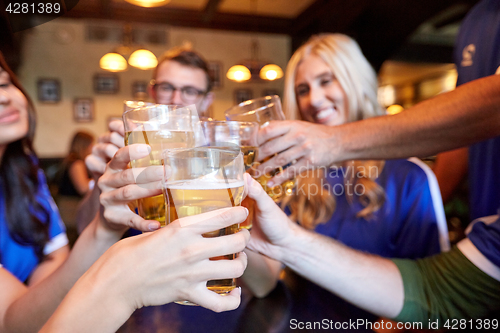 Image of football fans clinking beer glasses at sport bar