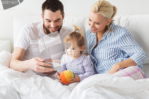 Image of happy family with smartphone in bed at home