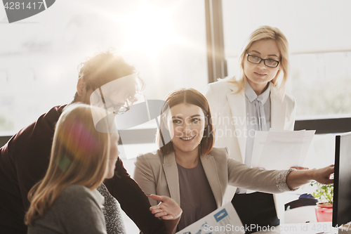Image of happy creative team with computer in office