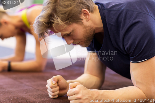 Image of close up of man at training doing plank in gym