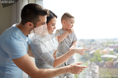 Image of happy family looking through window at home