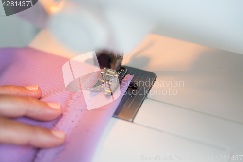 Image of sewing machine presser foot stitching fabric
