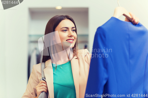 Image of happy young woman choosing clothes in mall