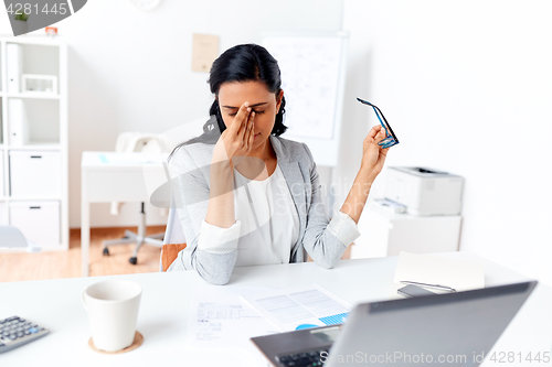 Image of businesswoman rubbing tired eyes at office