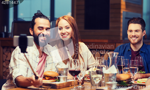 Image of friends taking selfie by smartphone at restaurant