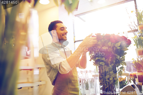 Image of smiling florist man with roses at flower shop