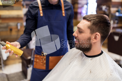 Image of barber showing hair styling spray to male customer