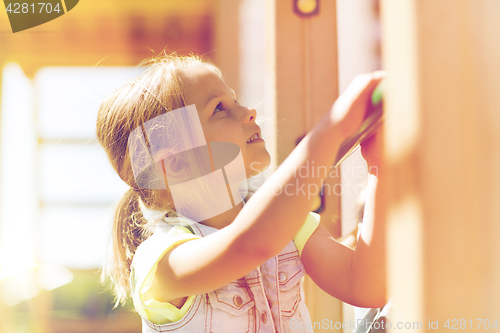 Image of happy little girl climbing on children playground