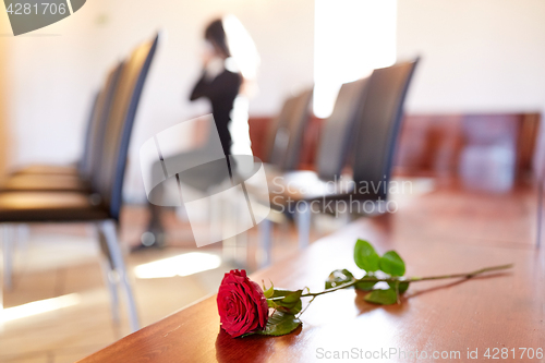 Image of red roses and woman crying at funeral in church