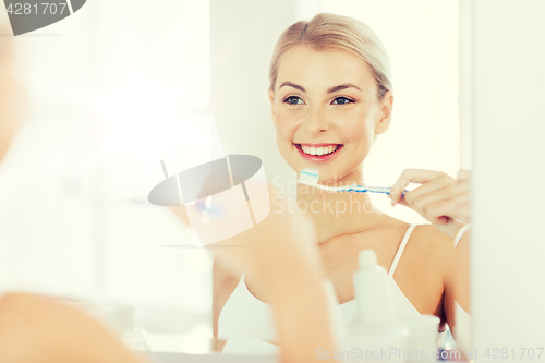 Image of woman with toothbrush cleaning teeth at bathroom