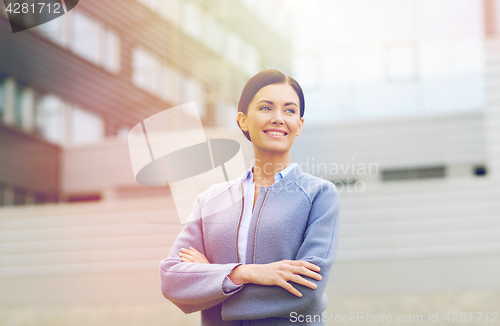 Image of young smiling businesswoman over office building