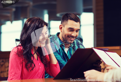 Image of smiling couple with menus at restaurant