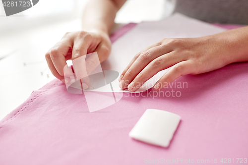 Image of woman with pins stitching paper pattern to fabric