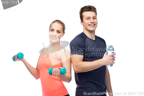 Image of sportive man and woman with dumbbell and water
