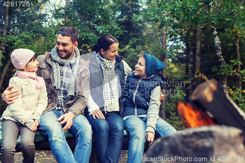 Image of happy family sitting on bench at camp fire