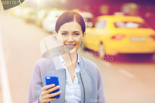 Image of smiling woman with smartphone over taxi in city