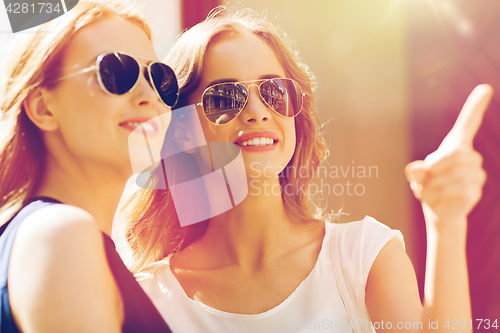 Image of happy women in sunglasses pointing finger outdoors