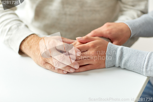 Image of close up of old man and young woman holding hands