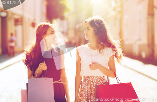 Image of happy women with shopping bags walking in city 
