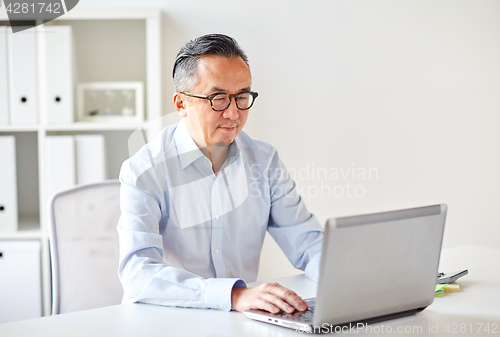 Image of businessman in eyeglasses with laptop office