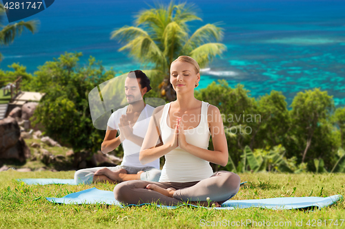 Image of happy couple doing yoga and meditating outdoors