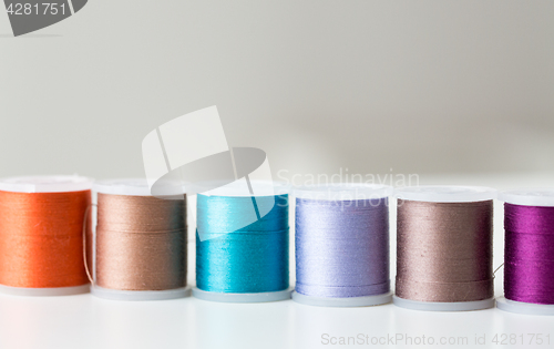 Image of row of colorful thread spools on table